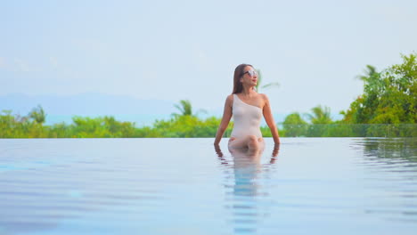 Schöne-Asiatische-Frau,-Die-Im-überlaufpoolwasser-Mit-Sexy-Badeanzug-Sitzt