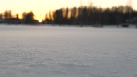 Snow-covered-ground-while-strong-wind-blowing-snow-and-sunset-in-background