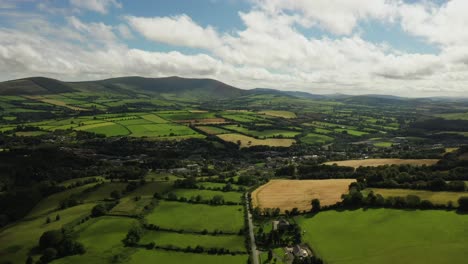 Irish-rural-landscape,-Aughrim,-Wicklow-August-2020,-Drone-gradually-pushes-towards-village-facing-South-towards-at-Toberlownagh-hills