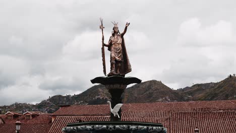 Golden-Atahualpa-statue-in-Main-plaza-cuzco-with-roofs-and-mountains---Timelapse