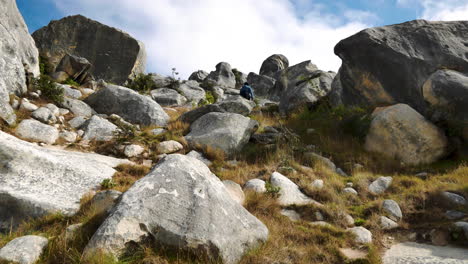 Close-up-shot-of-tourist-walking-uphill-between-famous-boulders-on-Castle-Hill-in-New-Zealand