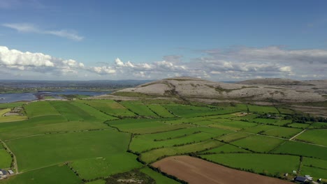 Irish-Rural-Landscape,-view-from-Aughinish-looking-towards-East-Burrin,-Clare,-Ireland,-August-2020,-Drone-gradually-ascends-while-pushing-towards-Burren-hills