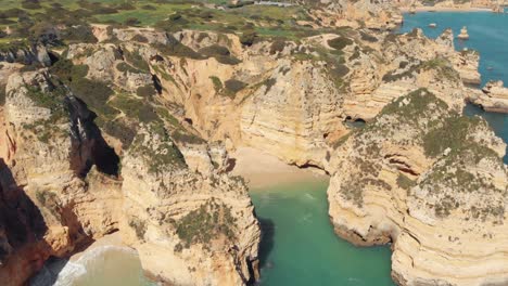 Isolated-Grotto-beach-surrounded-by-Nature-eroded-Cliffs-of-Ponta-da-Piedade,-Lagos,-Algarve---Aerial-Panoramic-tracking-shot
