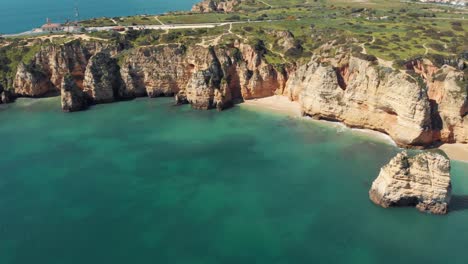 Algarve-limestone-Coastline-barring-emerald-green-mediterranean-sea---Aerial-high-Fly-over-push-in-shot