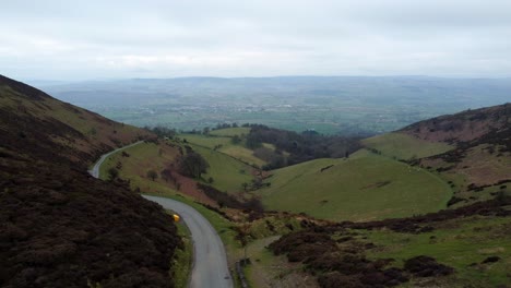 Narrow-single-rural-road-running-through-Welsh-green-mountain-valleys-landscape-aerial-right-dolly