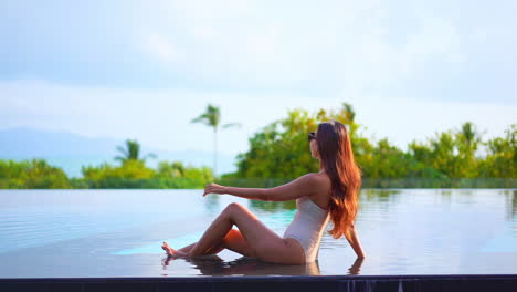Poised-on-the-edge-of-a-resort-swimming-pool-a-pretty-woman-looks-out-to-the-ocean-beyond