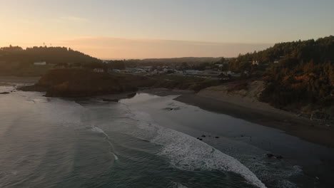 Drone-over-Oregon-beach-at-sunset,-small-town-of-Port-Orford