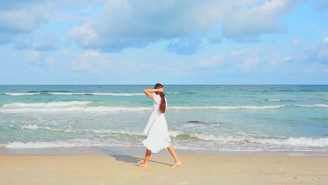 slow-motion-A-young-woman-dressed-in-a-loose-sundress-walks-along-the-beach