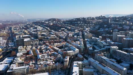 Aerial-panning-and-tilting-across-beautiful-city-skyline-with-red-tile-roofs,-streets-and-mountains-covered-in-snow-during-winter-in-Stuttgart,-Germany