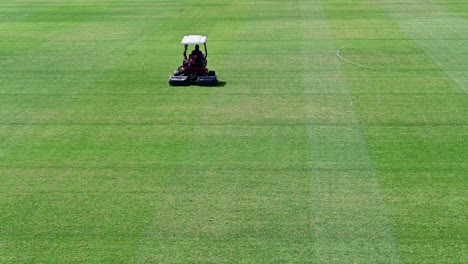 4k-Footage:-A-staff-on-a-lawn-mowing-vehicle-prepare-a-sports-field-on-a-sunny-summer-day-in-Dubai,-United-Arab-Emirates
