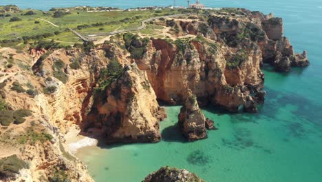 Vista-Lejana-Del-Faro-Ponta-Da-Piedade-Con-Vistas-Al-Océano-Atlántico-Y-Acantilados-Erosionados,-Lagos,-Algarve