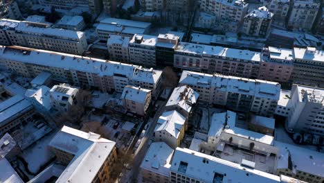 Aerial-top-down-view-flying-towards-beautiful-city-center-and-tilting-down-red-tile-roofs-and-streets-covered-in-snow-during-winter-in-Stuttgart,-Germany