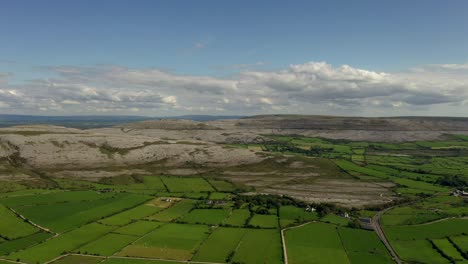 Irish-Rural-Landscape,-view-from-Aughinish-looking-towards-East-Burrin,-Clare,-Ireland,-August-2020,-Drone-gradually-tracks-parallel-to-Burren-hills