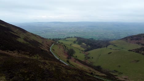 Narrow-single-rural-road-running-through-Welsh-green-mountain-valleys-landscape-aerial-dolly-right