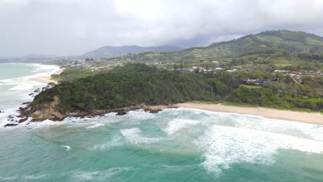 Idyllic-Scenery-Of-Ocean-Waves-Washing-On-Sandy-Beach-With-Lush-Vegetation-And-Mountains-In-Sapphire-Beach,-Coffs-Harbour,-NSW,-Australia---aerial-drone-shot