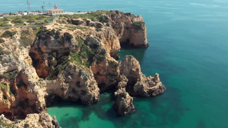 Stunning-scarps-surrounding-Ponta-da-Piedade-lighthouse,-Lagos-Algarve,-Portugal---Wide-aerial-Panoramic-Orbit-shot