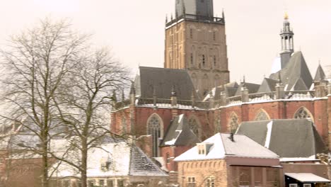 Walburgiskerk-rising-above-winter-barren-trees-part-of-the-cityscape-of-Hanseatic-city-Zutphen,-The-Netherlands,-covered-in-snow