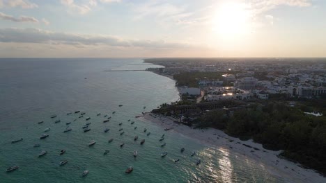 Boats-docked-in-the-ocean-near-the-beach-on-the-bay-Aerial-Summer-Sunset,-Playa-del-Carmen,-Yucatan,-Mexico