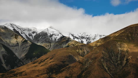 Toma-Panorámica-De-Cimas-De-Montañas-Cubiertas-De-Nieve-Y-Nubes-Blancas-En-El-Fondo-En-La-Colina-Del-Castillo,-Nueva-Zelanda