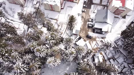 Flying-Over-Pine-Trees-And-Block-Of-Flats-Covered-With-Snow