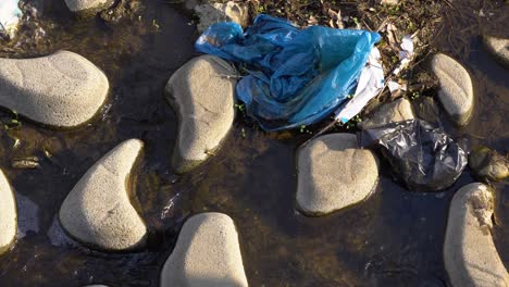 Plastic-Waste-On-Rocks-Of-An-Urban-River-At-Yangjaecheon-Stream-In-Seoul,-South-Korea
