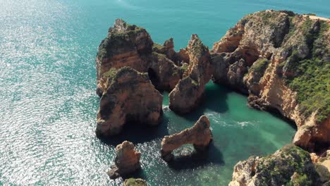 Top-view-of-enclosure-of-rocky-formations-in-Ponta-da-Piedade,-Algarve,-Lagos,-Portugal---Aerial-Descending-fly-over-shot