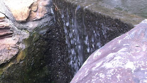 Flujo-De-Agua-Sobre-El-Borde-De-Una-Pequeña-Cascada-De-Jardín