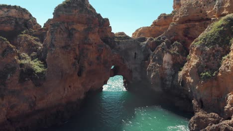 Arcos-Rocosos-Naturales-En-La-Escarpada-Costa-De-Lagos,-En-Algarve,-Portugal---Toma-Aérea-Sobrevuelo-A-Nivel-Del-Suelo
