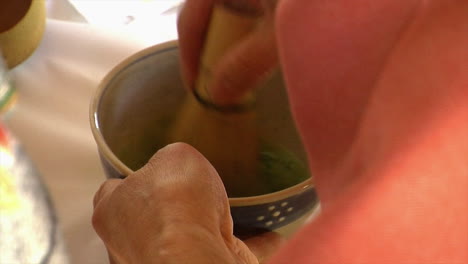 Close-up-of-bamboo-whisk-stirring-matcha-tea-in-a-Japanese-style-tea-bowl