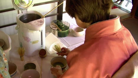 Japanese-woman-prepares-matcha-green-tea-with-bamboo-whisk-and-ladle