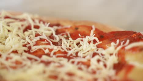 Adding-Grated-Cheese-to-Pizza-Topping,-Extreme-Close-up-with-Copy-Space