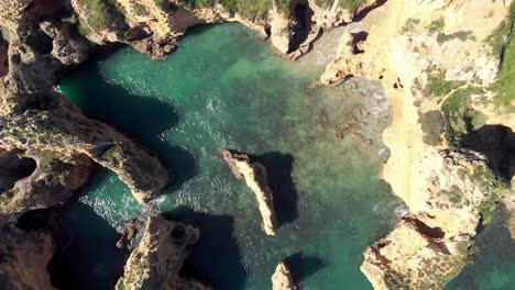 Rotating-bird's-eye-view-of-cliffs-and-rock-formations-of-Atlantic-sea-coastline,-Lagos,-Algarve