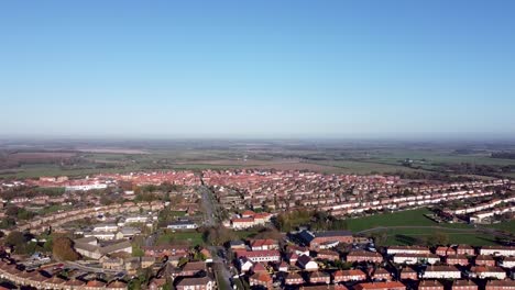 Aerial-truck-shot-showing-the-landscape-over-a-rural-village-in-the-southeast-of-England,-bright-bluesky-day