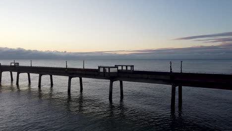 Low-angle-dawn-aerial-descending-view-across-Deal-pier-boardwalk-Kent-ocean-landmark