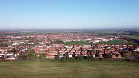 Aerial-dolly-shot-over-a-rural-village-in-England,-on-a-blue-sky-summer's-day