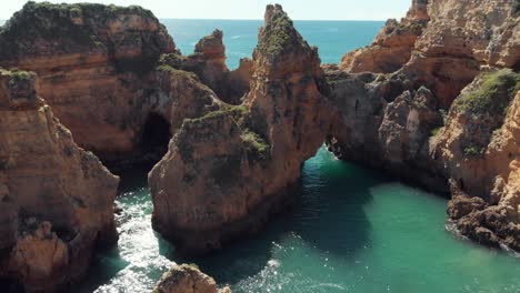 Idyllic-Grottos-and-rocky-eroded-archways-near-Ponta-da-Piedade,-Lagos,-Algarve,-Portugal---Aerial-Low-Orbit-shot
