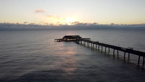 Relaxing-rippling-warm-sunrise-ocean-Deal-pier-Kent-aerial-static-landmark-shot