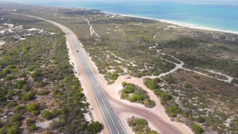 Aerial-shot-of-one-car-driving-through-nice-and-clean-Australian-rural-Road-front-to-ocean-during-sunny-day