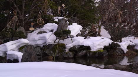 Slow-tilt-up-over-beautiful-Japanese-landscape-garden-with-pond-in-winter
