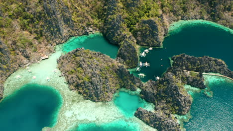 Aerial-shot-tilting-down-to-show-outrigger-boats-on-Matinloc-island,-El-Nido,-Palawan,-Phillipines