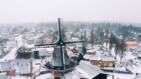 Aerial---Windmill-in-Garderen,-Netherlands-in-a-snowy-winter,-wide-circle-shot
