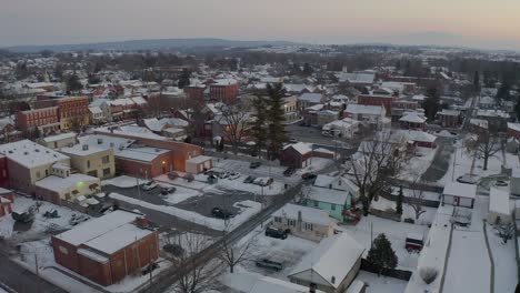 Aerial-establishing-shot-of-small-town-in-USA,-covered-in-snow-at-sunset,-sunrise