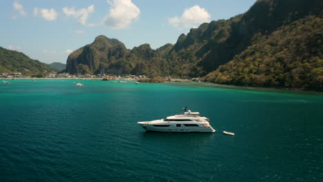 Aerial-showing-big-yacht-in-front-of-the-harbour-of-El-Nido,-Palawan,-Pilippines