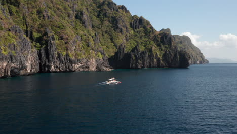 Flying-to-a-outrigger-boat-beside-Matinloc-Island,-El-Nido,-Palawan,-Philippines