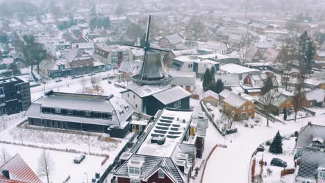 Aerial-shot-of-a-snowed-dutch-village-with-a-typical-windmill