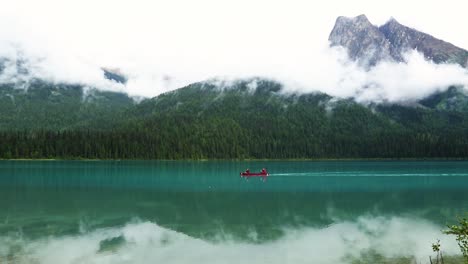 Two-People-Kayaking-Canoeing-On-a-Beautiful-Peaceful-Blue-Lake-With-Huge-Cloudy-Rocky-Mountains-In-Background-and-Reflection-on-Lake,-Canada-National-Parks