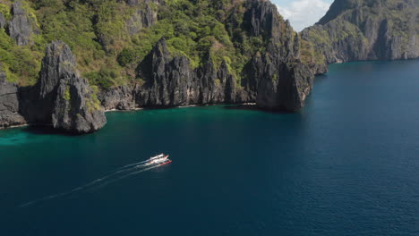 Aerial-showing-outrigger-boat-nearby-Matinloc-Island,-El-Nido,-Palawan,-Philippines