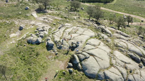 Cyclists-gathering-in-Mountain-Peak-large-Boulder-in-Minho,-Portugal---Aerial-Top-Orbit-shot