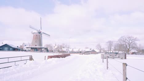 Farms-and-a-windmill-in-a-snowy-winter-in-Ermelo,-Netherlands,-wide-shot