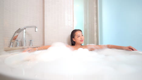 Young-asian-woman-relaxes-in-bathtub-with-foam